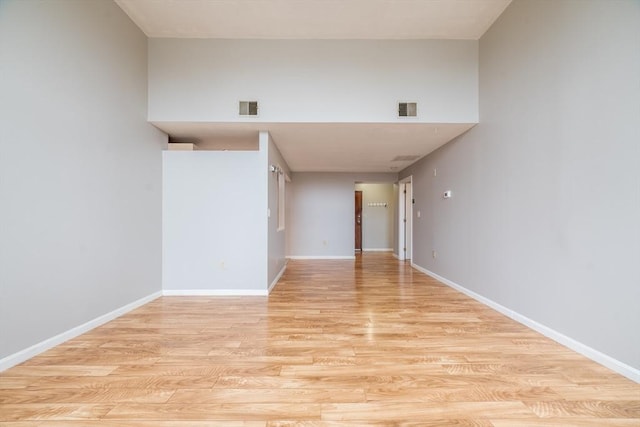 empty room featuring light wood-type flooring, baseboards, and visible vents