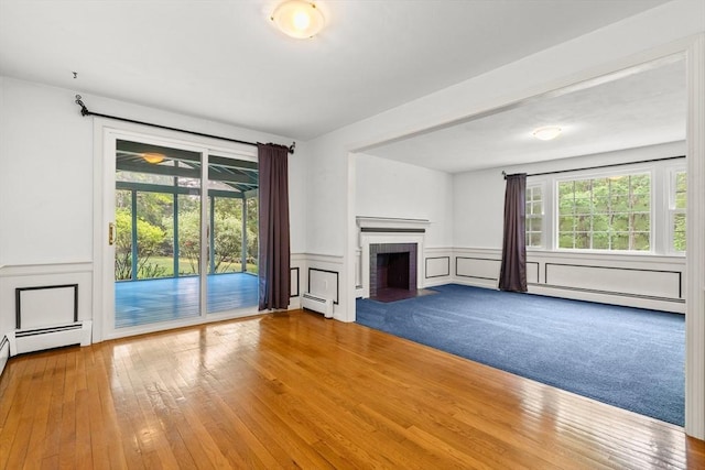 5 Ingalls Rd, Tyngsborough, MA 01879 - unfurnished living room featuring a brick fireplace, plenty of natural light, a decorative wall, a baseboard radiator, and wood-type flooring