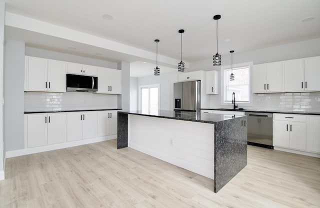664 Mckinstry Ave, Chicopee, MA 01020 - kitchen with appliances with stainless steel finishes, a sink, light wood finished floors, decorative backsplash, and a center island