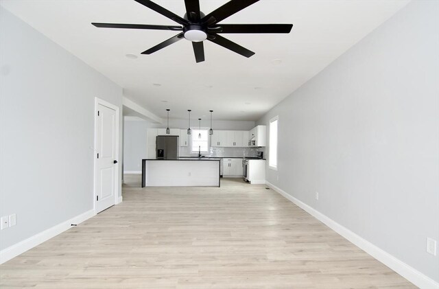 664 Mckinstry Ave, Chicopee, MA 01020 - unfurnished living room with a ceiling fan, baseboards, and light wood-style floors