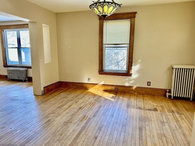 spare room featuring radiator, an inviting chandelier, and light hardwood / wood-style floors