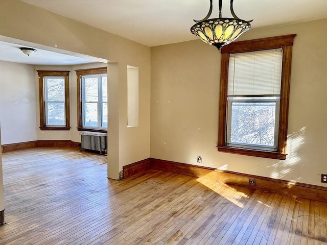 spare room with a chandelier, radiator, and light hardwood / wood-style flooring