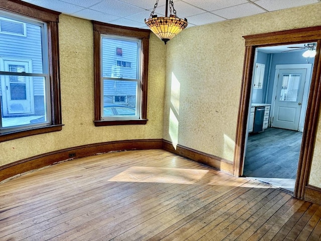 spare room with a paneled ceiling and hardwood / wood-style floors