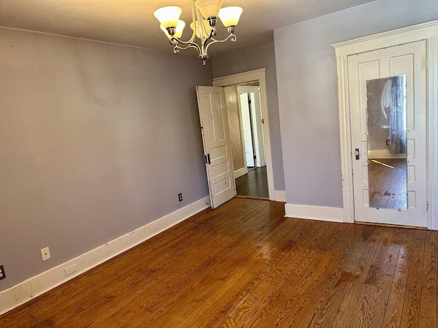 unfurnished bedroom featuring an inviting chandelier and dark wood-type flooring