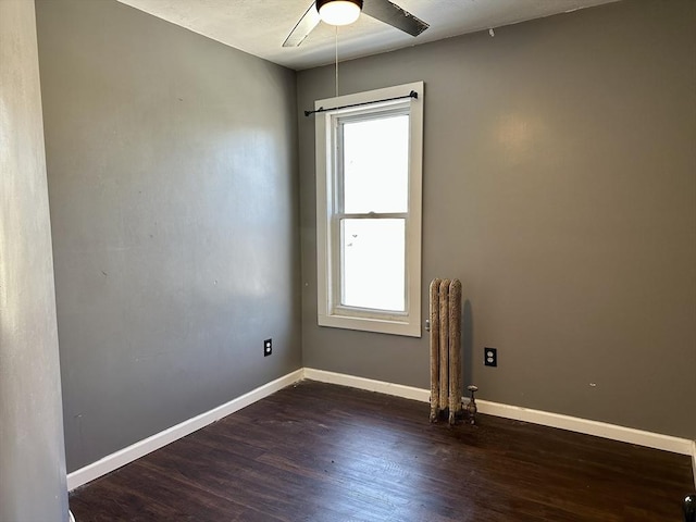 unfurnished room with dark wood-type flooring, radiator heating unit, and ceiling fan