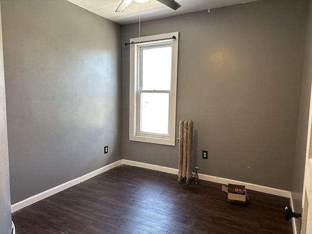 spare room featuring dark hardwood / wood-style flooring, radiator heating unit, and ceiling fan