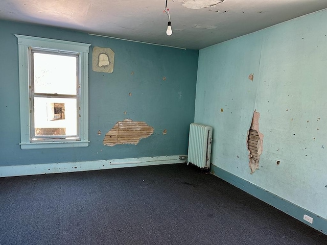 empty room with radiator and dark colored carpet