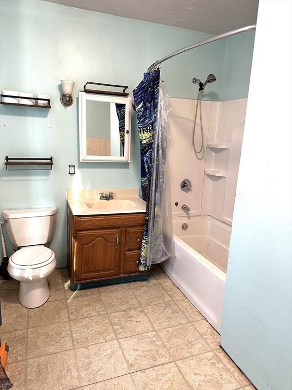 full bathroom with vanity, toilet, a textured ceiling, and shower / bath combo