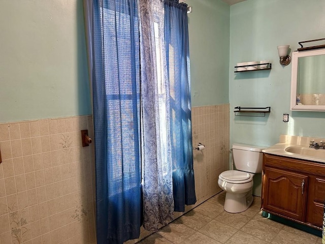 bathroom with vanity, tile walls, and toilet