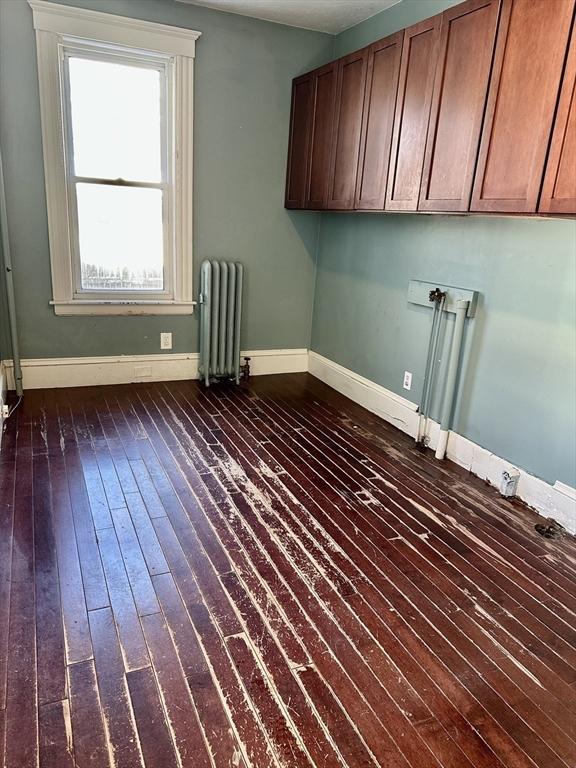 laundry room with radiator, dark hardwood / wood-style floors, and cabinets