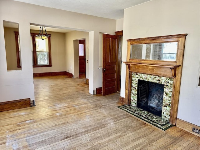 unfurnished living room featuring light hardwood / wood-style flooring and a tile fireplace