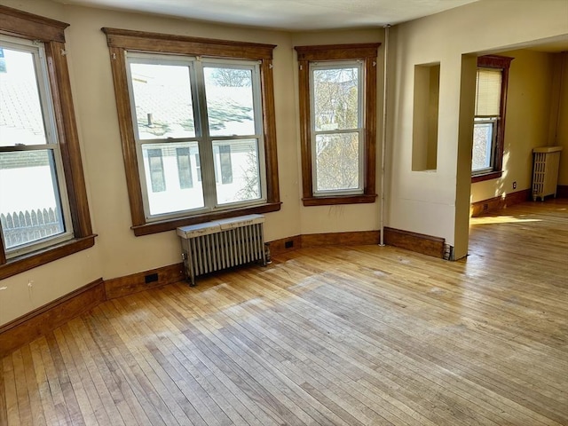 empty room with light hardwood / wood-style flooring and radiator heating unit