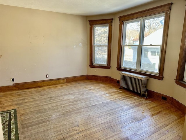 spare room featuring radiator and light hardwood / wood-style floors