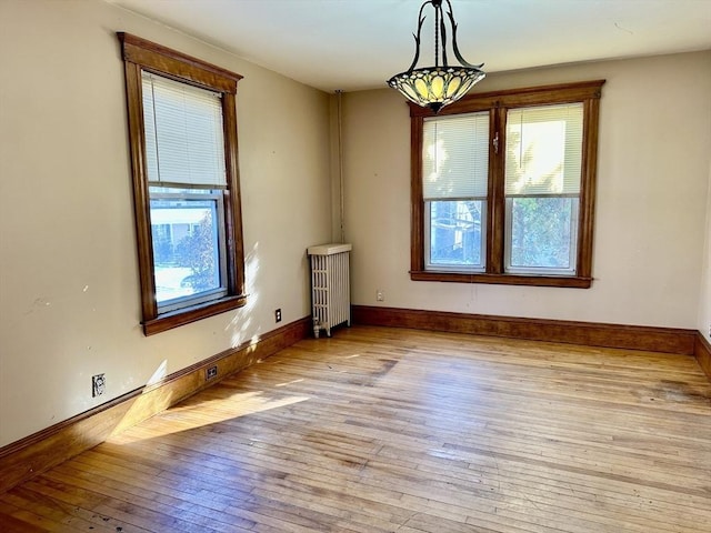 empty room with radiator heating unit and light hardwood / wood-style floors