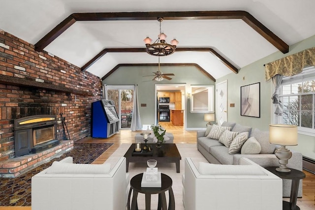 living room featuring ceiling fan with notable chandelier, a fireplace, lofted ceiling with beams, and wood finished floors