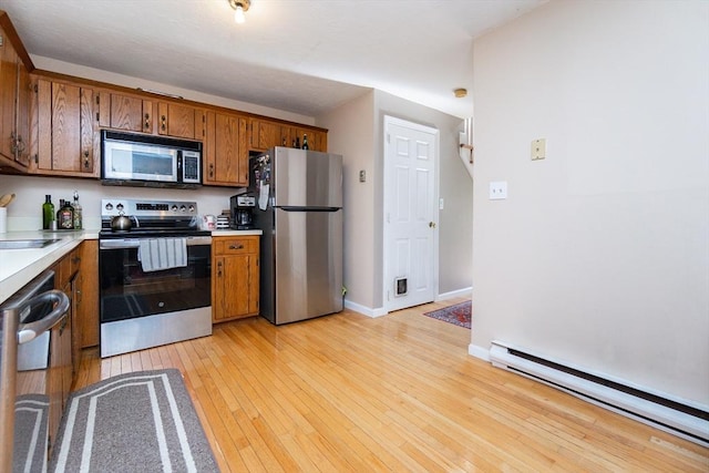 60 Spencer St Unit 60, Millis, MA 02054 - kitchen with appliances with stainless steel finishes, a baseboard heating unit, brown cabinetry, and light countertops