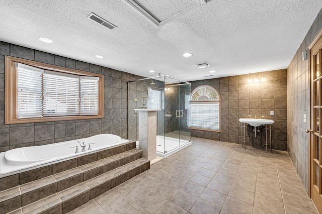 bathroom featuring tile walls, tile floors, plenty of natural light, and a textured ceiling