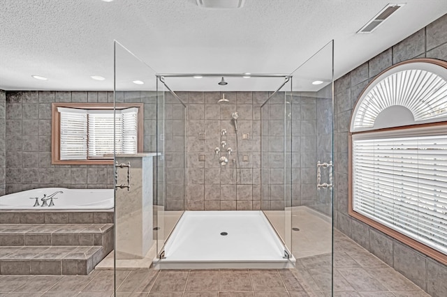 bathroom with independent shower and bath, tile floors, plenty of natural light, and tile walls