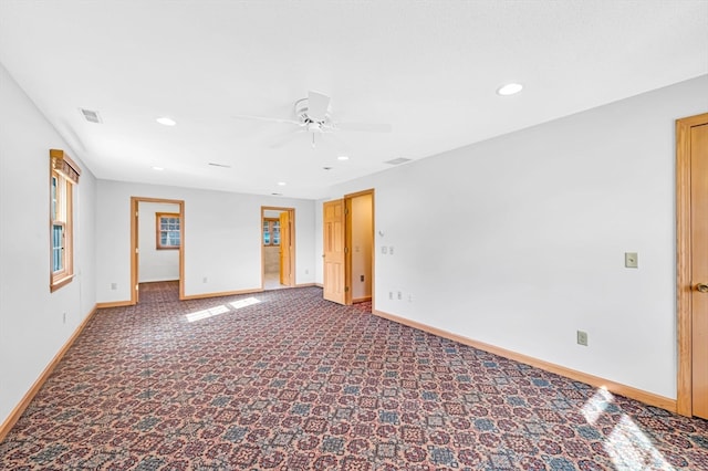 spare room featuring ceiling fan and dark colored carpet