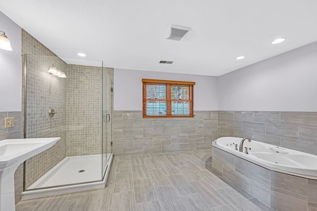 bathroom with tile walls, tile flooring, and separate shower and tub