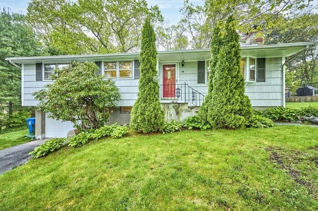 view of front of property with a garage, a front yard, and asphalt driveway