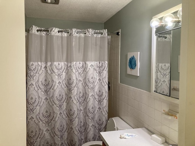 2 Summit Unit 68, Reading, MA 01867 - full bath with vanity, tile walls, a textured ceiling, a shower with shower curtain, and a wainscoted wall