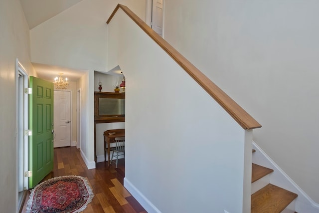 staircase with a high ceiling, hardwood / wood-style flooring, and a notable chandelier