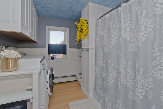 washroom with baseboard heating, light hardwood / wood-style flooring, and washer and dryer