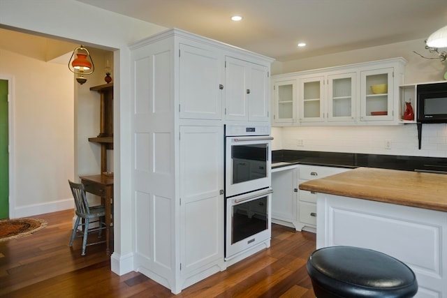 kitchen featuring dark hardwood / wood-style flooring, white double oven, backsplash, white cabinetry, and decorative light fixtures