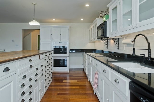 kitchen featuring white cabinets, dark hardwood / wood-style flooring, black appliances, and hanging light fixtures