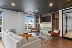 living room featuring built in shelves, a fireplace, and hardwood / wood-style floors