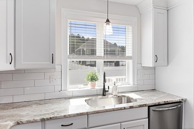 kitchen with white cabinets, light stone counters, stainless steel dishwasher, pendant lighting, and a sink