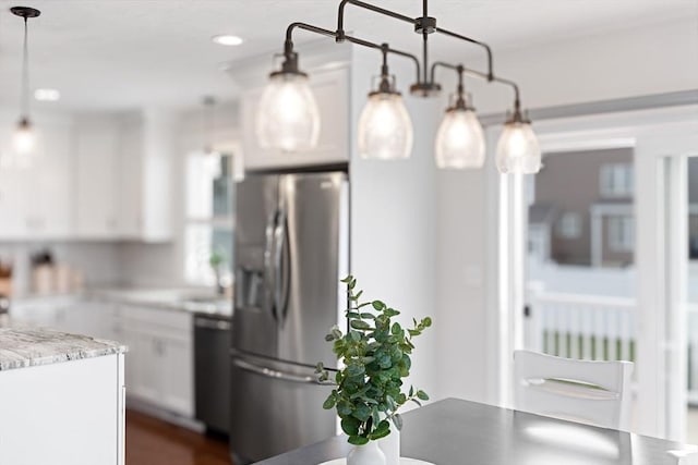 kitchen with light stone counters, white cabinets, hanging light fixtures, stainless steel refrigerator with ice dispenser, and dishwasher