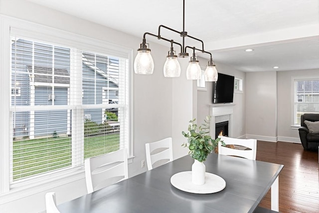 dining space featuring recessed lighting, dark wood-style flooring, a lit fireplace, and baseboards