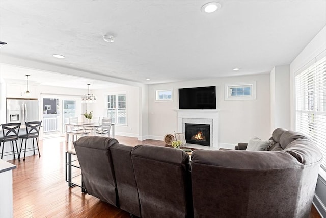 living area featuring a glass covered fireplace, recessed lighting, wood finished floors, and baseboards