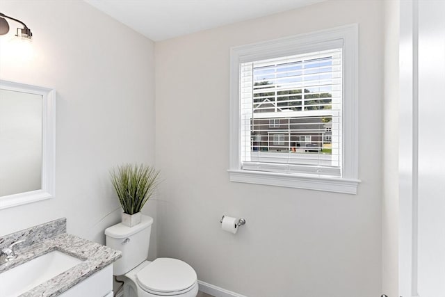 bathroom with toilet, vanity, and baseboards