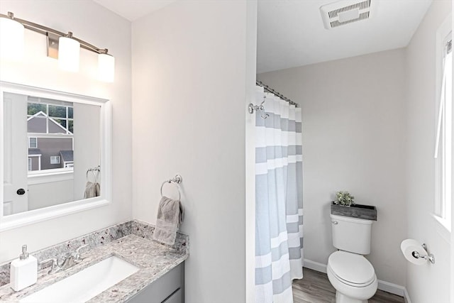 bathroom featuring toilet, a wealth of natural light, vanity, and visible vents