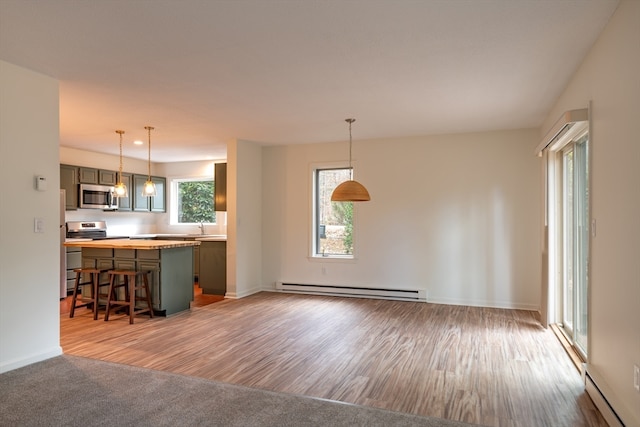 kitchen featuring a kitchen bar, appliances with stainless steel finishes, a baseboard radiator, and plenty of natural light