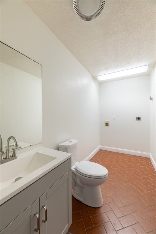 bathroom with vanity, a textured ceiling, and toilet