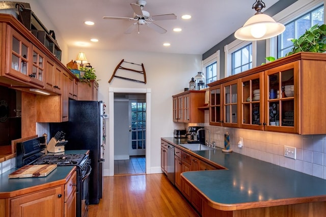 kitchen featuring ceiling fan, sink, black gas range, light hardwood / wood-style floors, and decorative light fixtures