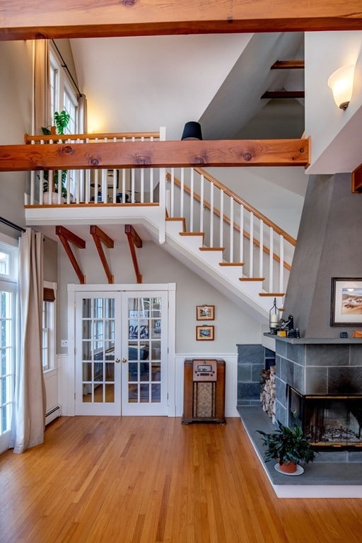 unfurnished living room featuring plenty of natural light, a baseboard heating unit, french doors, and light hardwood / wood-style flooring