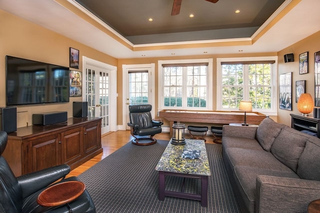 living room with ceiling fan, a tray ceiling, light hardwood / wood-style floors, and french doors