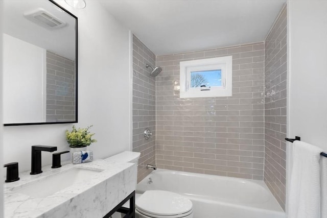 full bathroom with sink, tiled shower / bath combo, and toilet