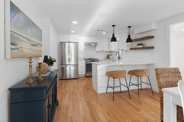 kitchen with sink, light hardwood / wood-style flooring, appliances with stainless steel finishes, white cabinets, and kitchen peninsula