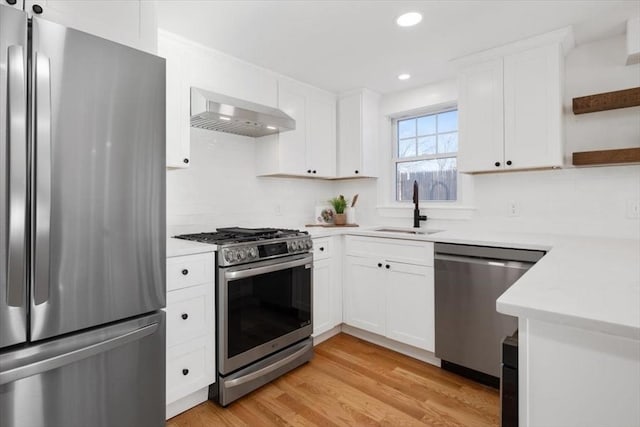 kitchen with white cabinetry, sink, wall chimney exhaust hood, stainless steel appliances, and light hardwood / wood-style flooring