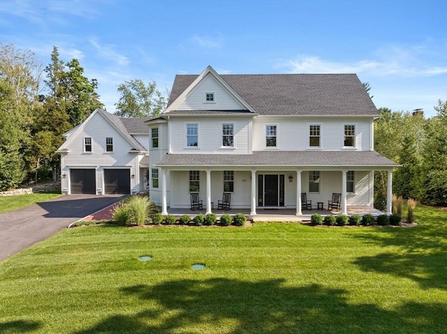 farmhouse featuring a garage, a porch, and a front yard