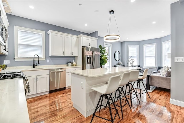 64 Clarkwood Unit 2, Boston, MA 02126 - kitchen featuring appliances with stainless steel finishes, a kitchen bar, plenty of natural light, light wood-type flooring, and recessed lighting