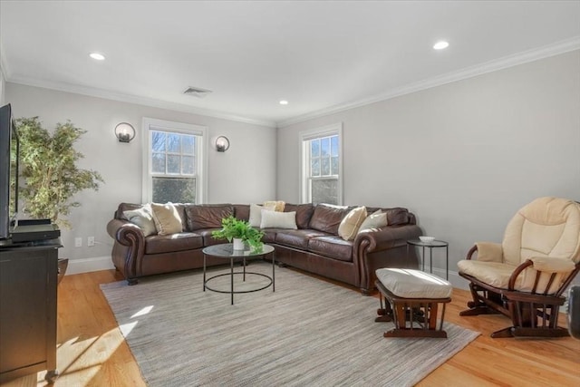 living room featuring a wealth of natural light, crown molding, light wood-style flooring, and baseboards