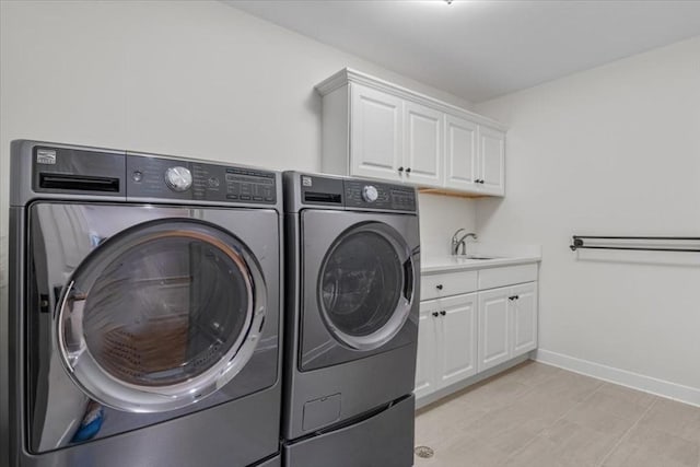 laundry room with a sink, washing machine and clothes dryer, cabinet space, and baseboards