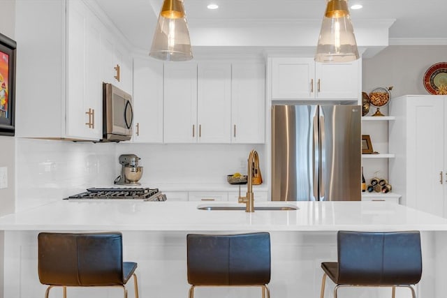 kitchen featuring a breakfast bar area, ornamental molding, appliances with stainless steel finishes, white cabinets, and a sink